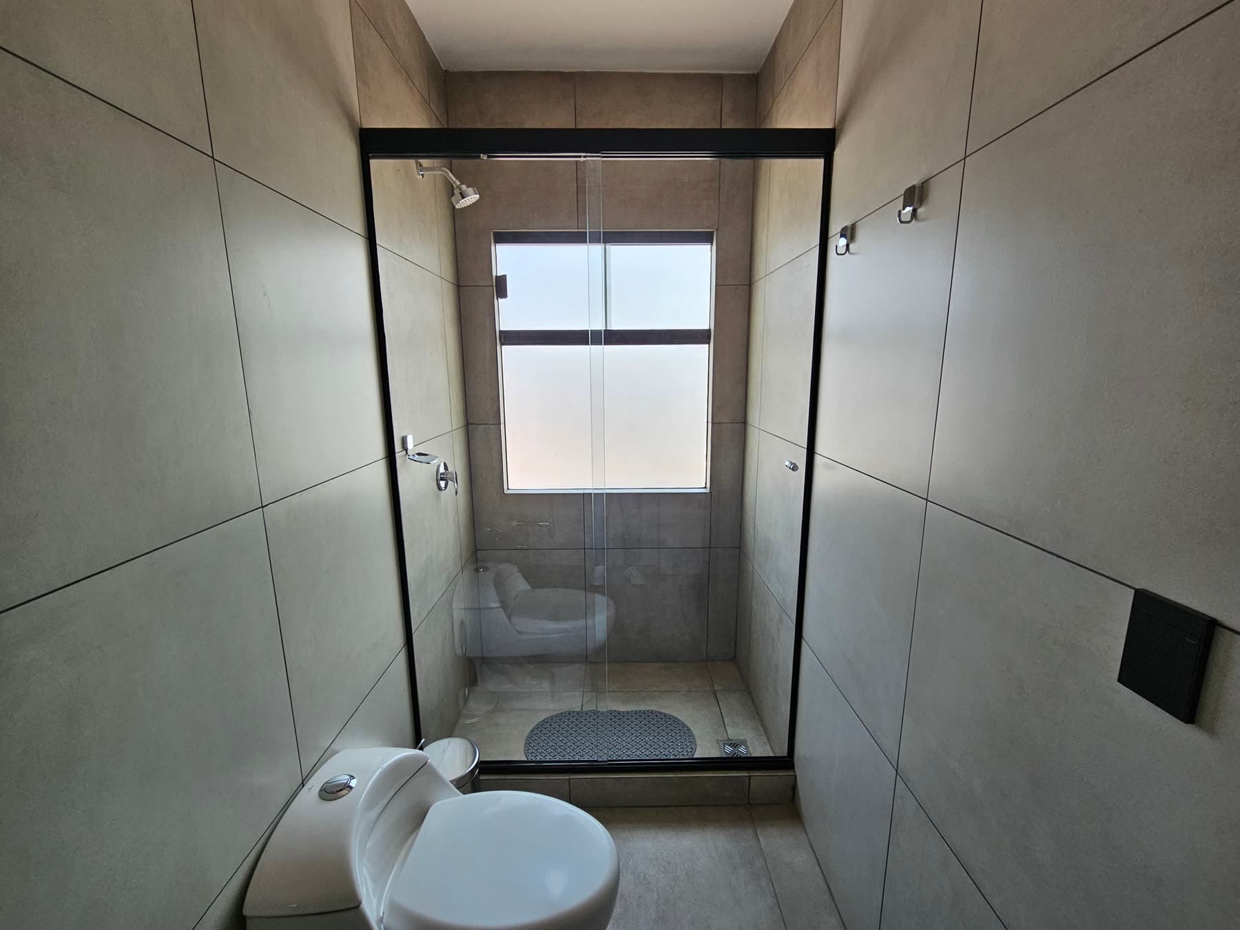 Baño con ducha, mampara de vidrio y ventana