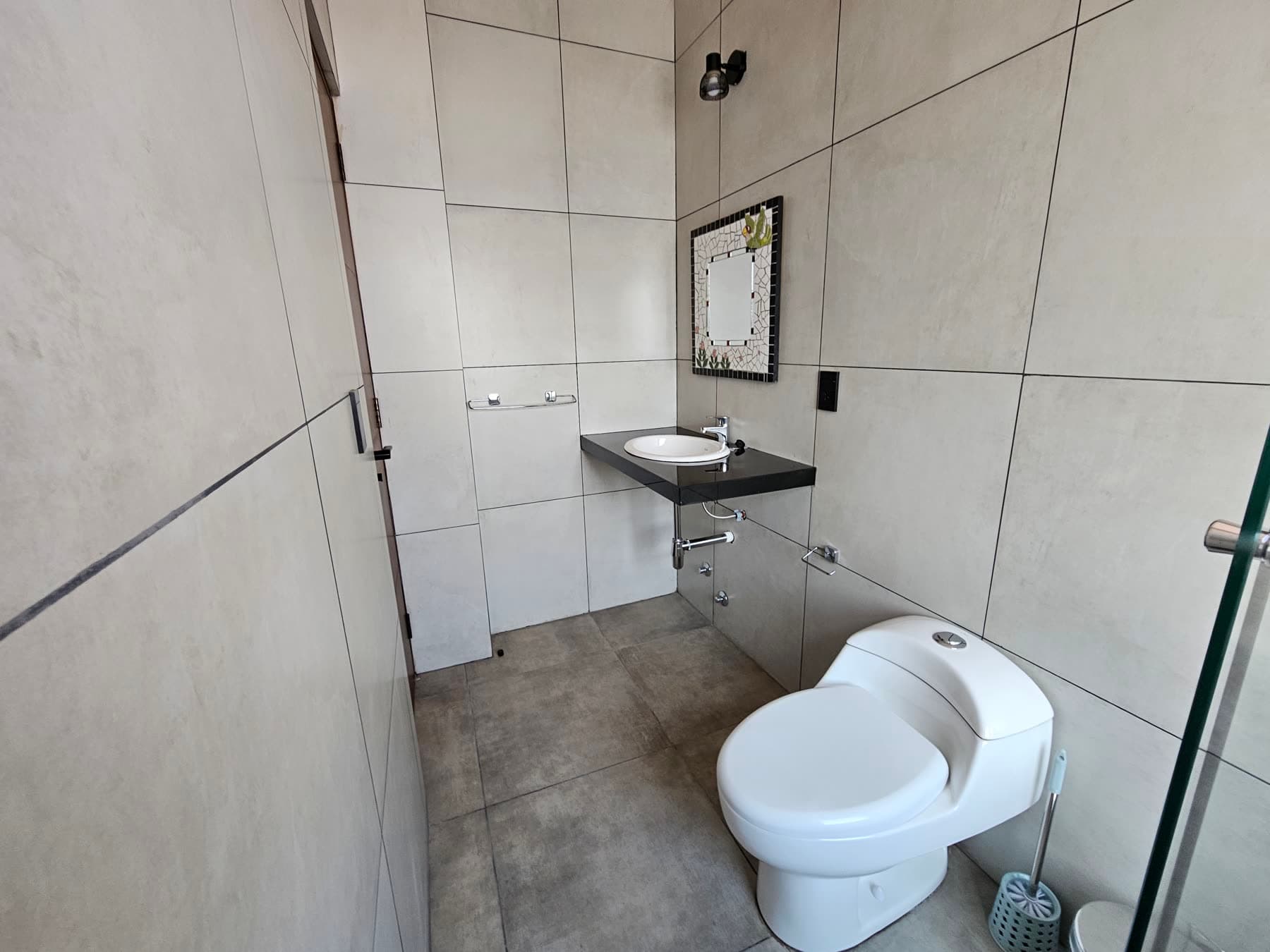 Baño desde el otro extremo, con lavamanos y espejo