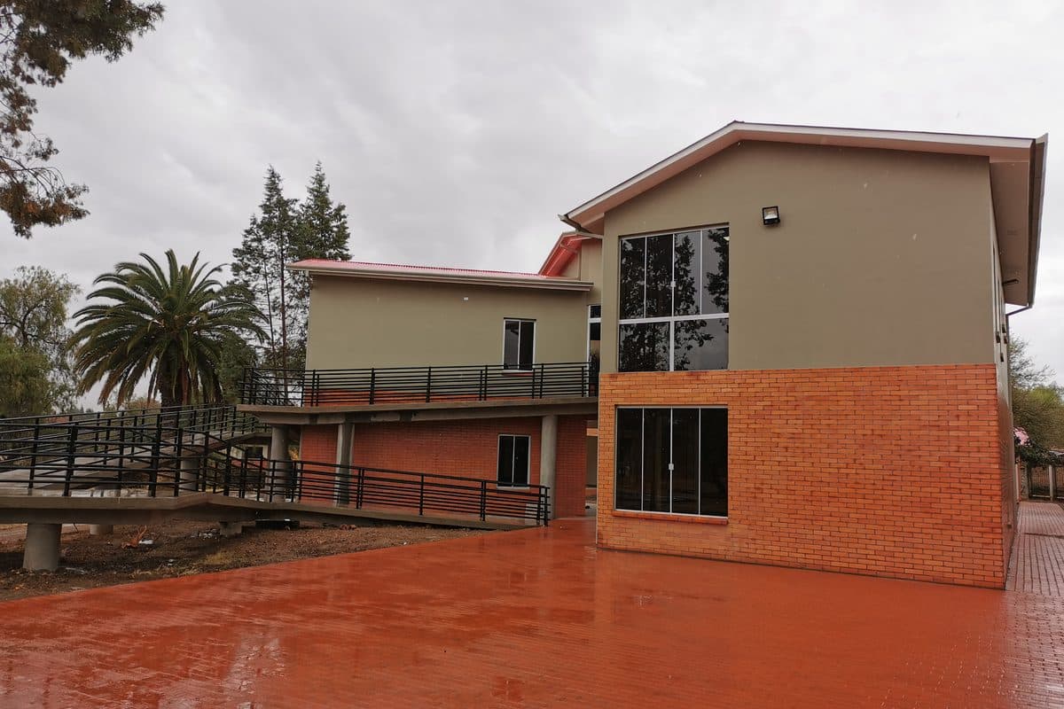Patio pavimentado del Colegio Andalucía con el bloque de aulas y la rampa al fondo